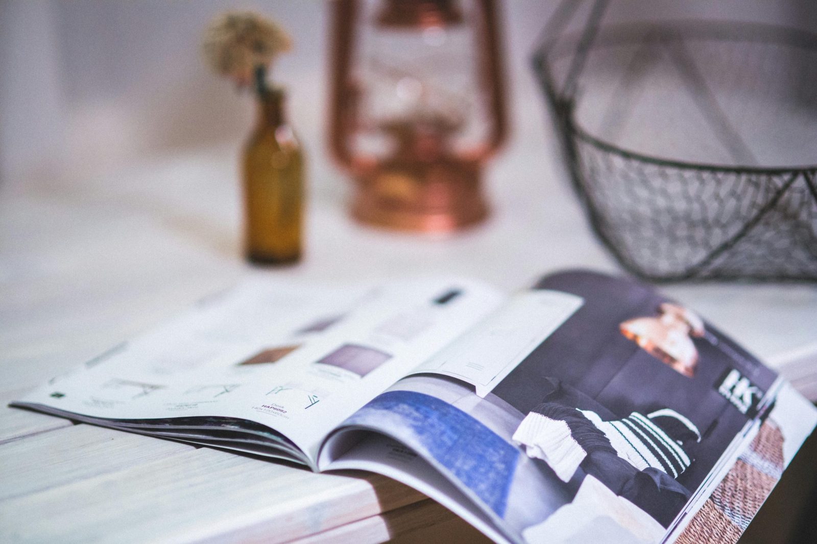 A stylish open magazine on a minimalistic desk with a blurred background.